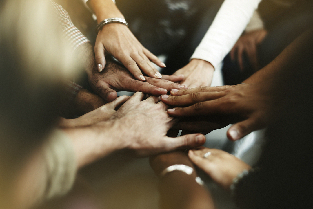 Cultura Organizacional: imagem fechada em diversas pessoas dando as mãos.
